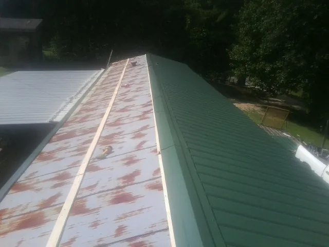 Old rusted panels beside newly installed green metal roofing — Wind Damage Roof Repair by Roofing Brothers in Ellettsville