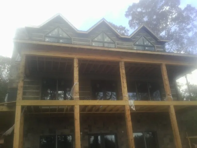 Dormers and porch framing on a large log home under construction — Roof Coating work by our crew in Ellettsville
