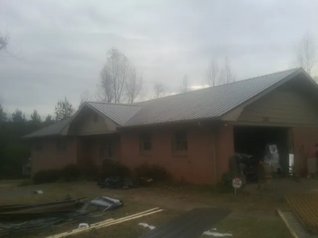 Gray metal roof on a stucco house with an attached garage in Ellettsville