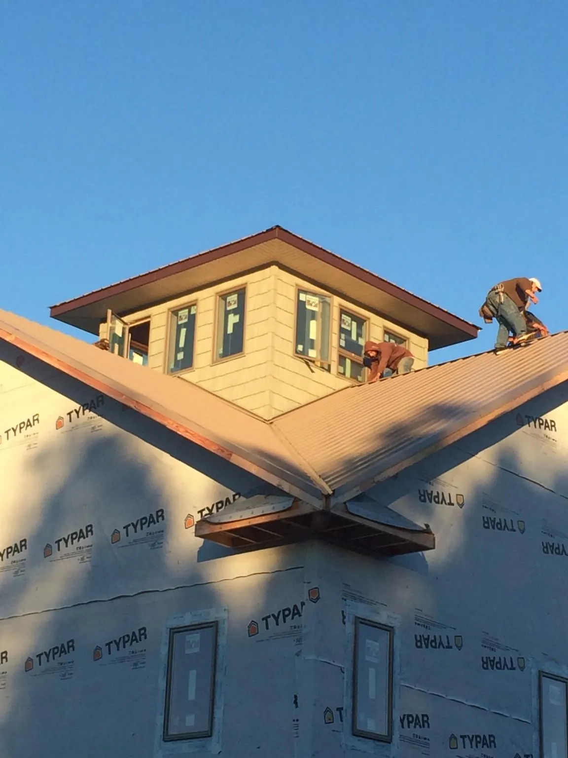 Roofers working around a rooftop cupola on a new metal roof at sunset — Roof Waterproofing in Ellettsville by Roofing Brothers